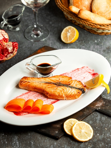 焼き鮭の側面図 ナルサラブザクロソースと白い皿にレモン添え 無料の写真