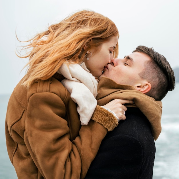 冬のキス中に湖のそばのカップルの側面図 無料の写真