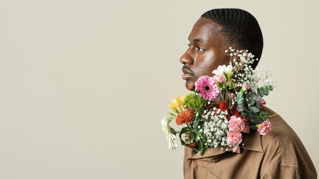 花の花束でポーズをとってハンサムな男の肖像画 無料の写真