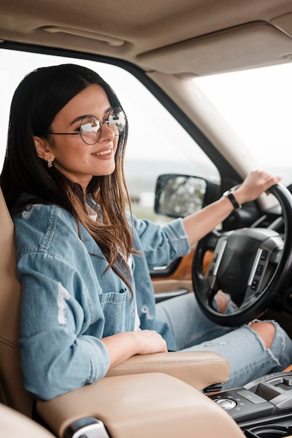 車で一人旅のメガネと笑顔の女性の側面図 無料の写真