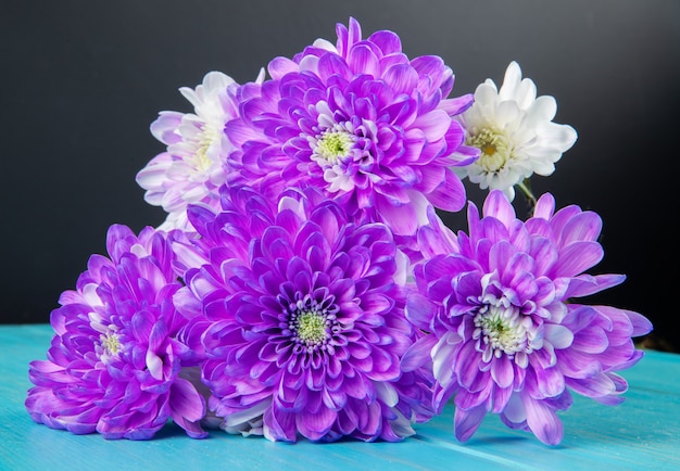 青と黒の背景で分離された紫と白の色の菊の花の花束の側面図 無料の写真