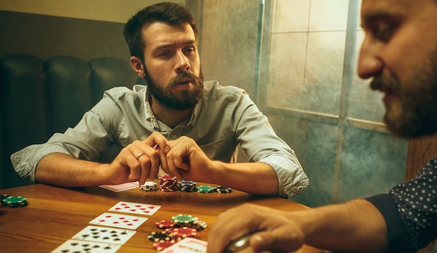 Foto Di Vista Laterale Di Amici Maschi E Femmine Seduti Al Tavolo Di Legno Uomini E Donne Che Giocano A Carte Mani Con Il Primo Piano Dell Alcool Foto Gratis