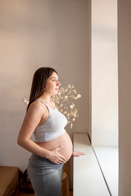 side-view-pregnant-woman-looking-out-the-window_23-2148366386.jpg