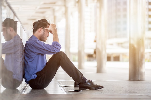 Premium Photo | Side view of a sad man with a hand on the head sitting ...