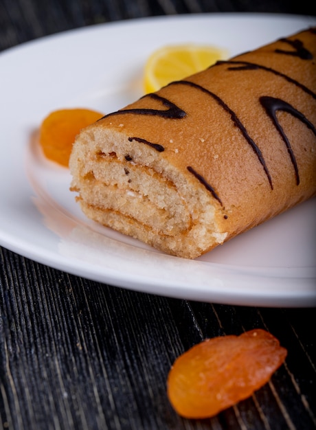 Free Photo | Side view of swiss roll with apricot jam on a white plate