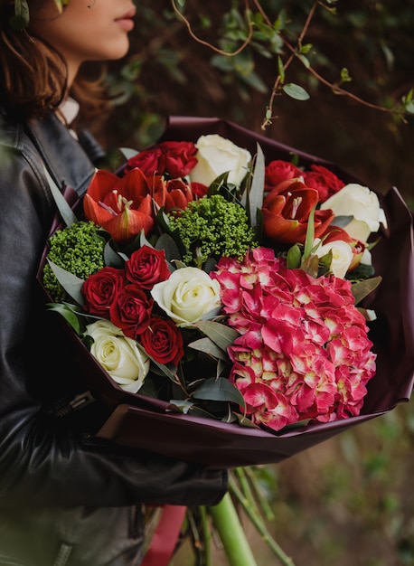 Vista Laterale Di Una Donna Che Tiene Un Mazzo Di Rose Di Colore Bianco E Rosso Con Tulipani Di Colore Rosso Colore Rosa Ortensia E Trachelium Fiori Da Parete Foto Gratis