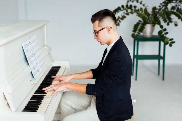 Side view of a young man playing grand piano | Free Photo