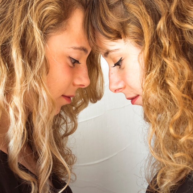 Free Photo | Side view of young sisters touching their forehead