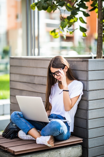 Low section of young woman using laptop while sitting on 