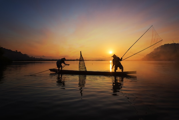 Premium Photo | Silhouette of asian fisherman on wooden boat