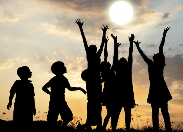 Premium Photo | Silhouette, group of happy children playing on meadow ...