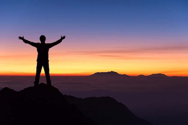 Premium Photo | Silhouette of man standing and spread hand on the top ...