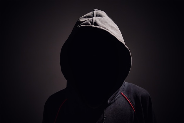 Premium Photo | Silhouette of man without face in hood on a black.