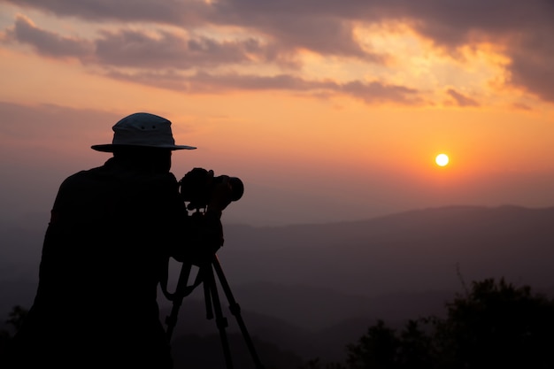 無料の写真 山の夕日を撮影する写真家のシルエット