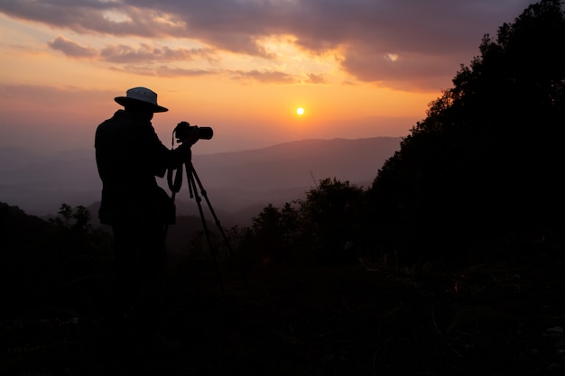 山の夕日を撮影する写真家のシルエット 無料の写真