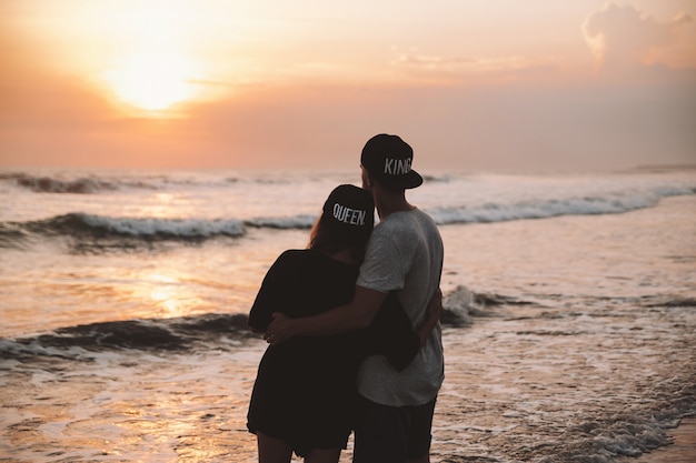 Silhouette portrait of young romantic couple walking on the beach. girl and her boyfriend posing at golden colorful sunset. they hugging and dreaming Free Photo