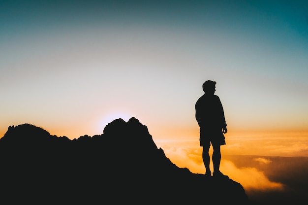 Free Photo | Silhouette shot of a man standing on a cliff looking at ...