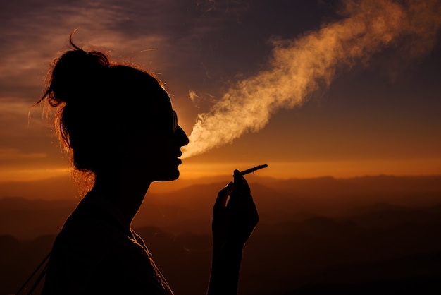 Premium Photo | Silhouette of smoking woman in sunset landscape