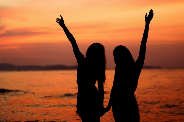 Premium Photo | Silhouette of two woman having fun on the sea beach