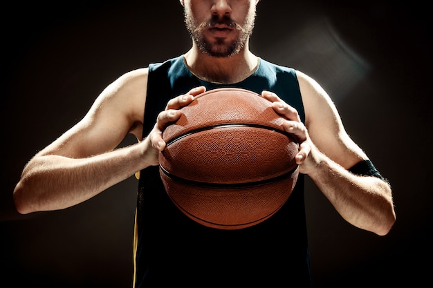 黒い​壁​に​バスケットボール​を​保持している​バスケットボール​選手​の​シルエットビュー 無料写真