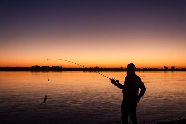 Premium Photo | Silhouette of a young man catching a fish with the ...