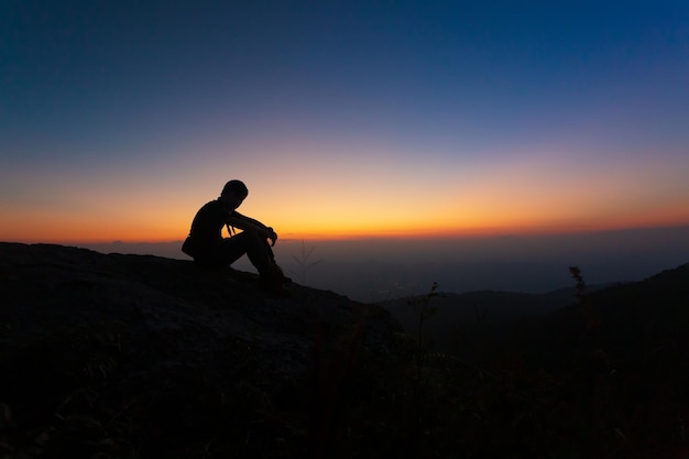 Premium Photo | Silhouette of young man sitting on top mountain view ...