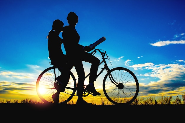 Premium Photo | Silhouettes couples and bicycle on sunset sky, couples ...