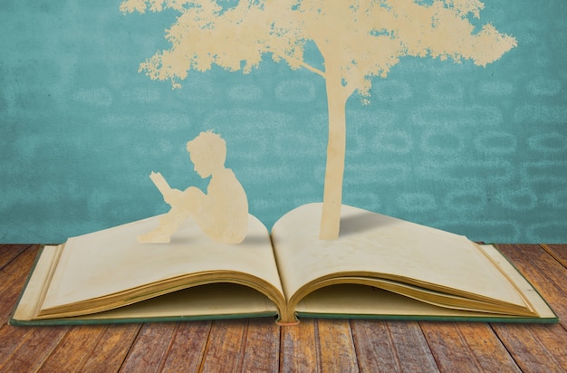 Silhouettes of a tree and a man on a book Free Photo