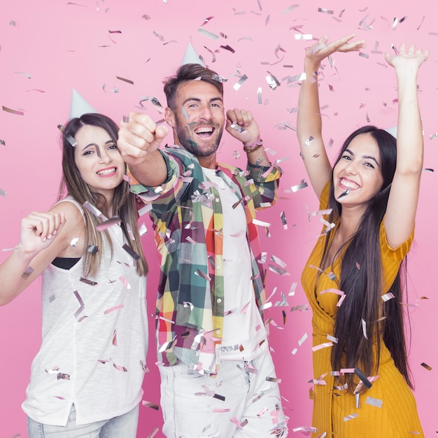 Silver confetti falling over the friends dancing against pink background Free Photo