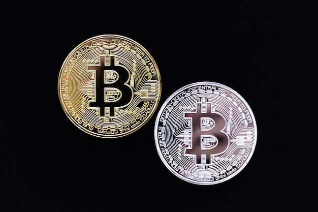 Silver and gold bitcoins on black background. Premium Photo