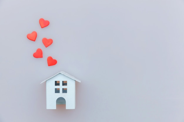 Simply minimal design with miniature white toy house with red heart isolated on white Premium Photo