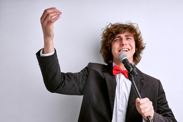 白い背景で隔離のポーズのスーツの歌手の男 人々のライフスタイルの概念 男性がマイクで歌を歌う プレミアム写真