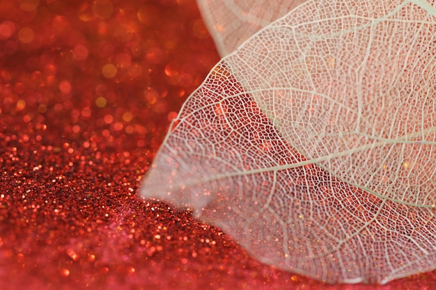 スケルトンは 輝くボケ味のある赤いキラキラ背景にスケルトンの葉を残します壁紙電話輝くキラキラ輝くボケ味の美しい自然の背景 プレミアム写真