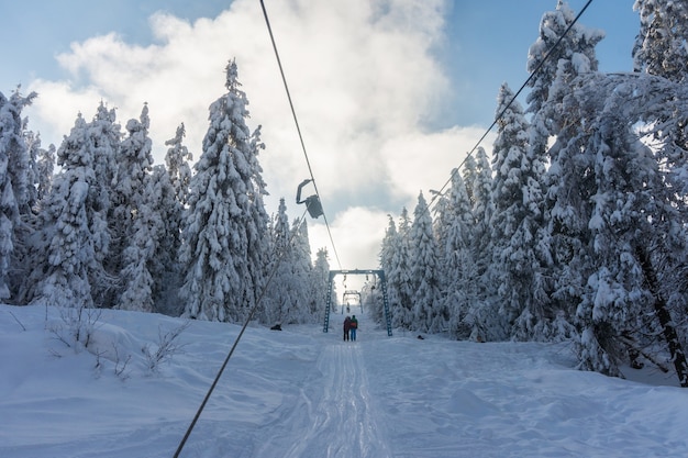 Premium Photo | Skiers on a ski lift on snowy mountainside