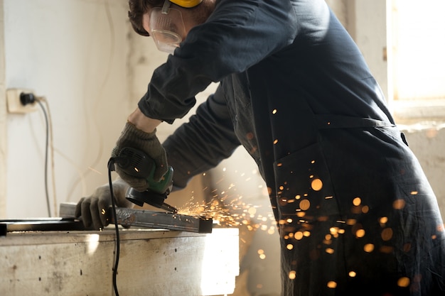 Skilled workman grinding metal profile pipe with lot of sparks  Photo | Free Download