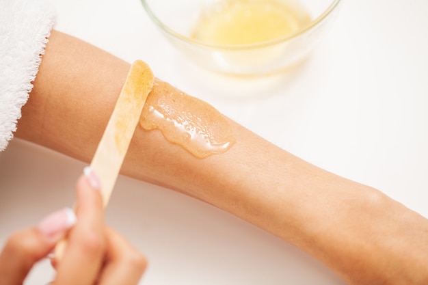 Premium Photo | Skin care, a woman applies wax to her hand to remove hair