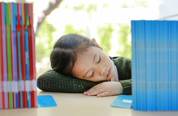 Sleeping Asian Little Child Girl On Bookshelf At Library Premium