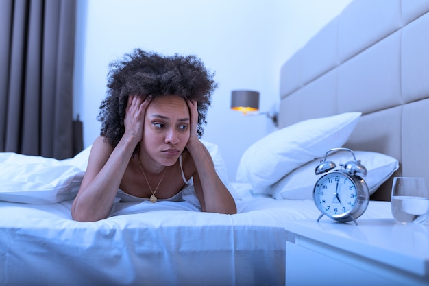 Premium Photo | Sleepless and desperate woman awake at night not able to sleep, feeling frustrated and worried looking at clock suffering from insomnia in sleep disorder concept.