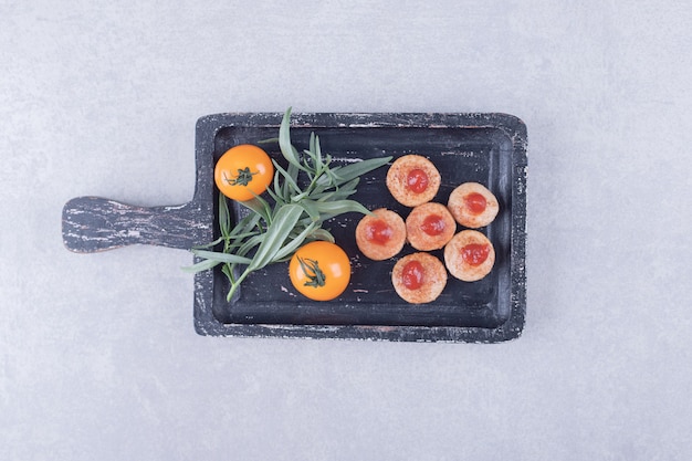 Free Photo Sliced Sausages With Ketchup And Tomatoes On Black Board