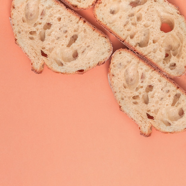 Slices of fresh bread with copy space on peach backdrop Free Photo