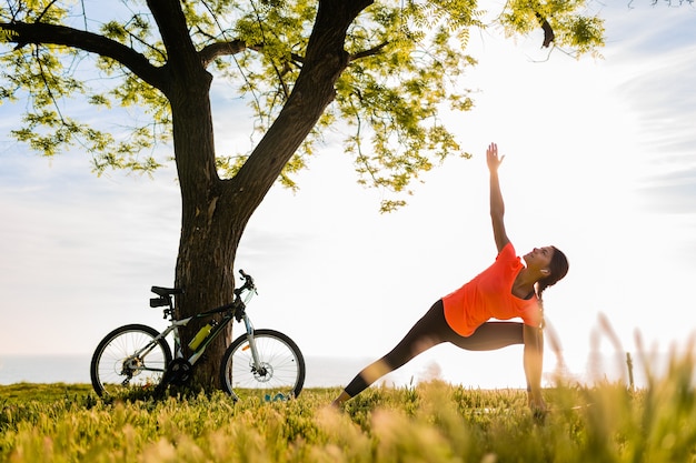 Slim beautiful woman silhouette doing sports in morning in park doing yoga Free Photo