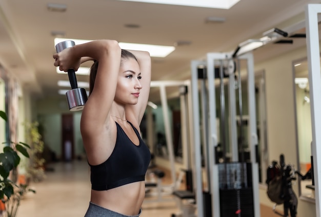 Premium Photo | Slim fit woman in sportswear doing extension exercise from  behind the head with dumbbells in her hands at the gym. healthy lifestyle  concept