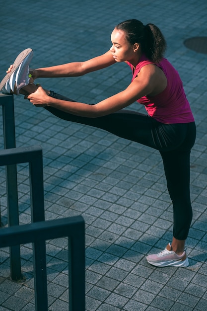 Premium Photo | Slim sportswoman in the street stretching muscles by ...