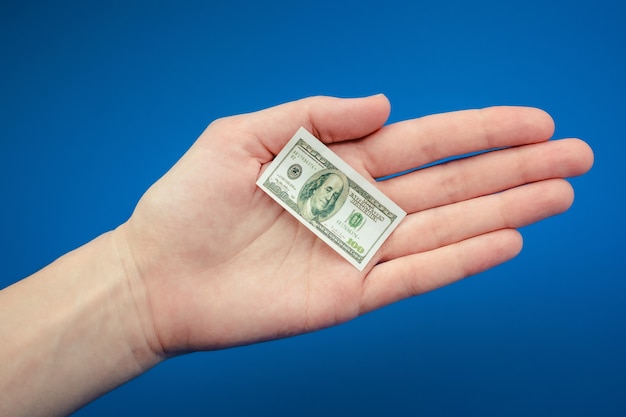 Premium Photo | Small american dollar bill in hand on a blue background