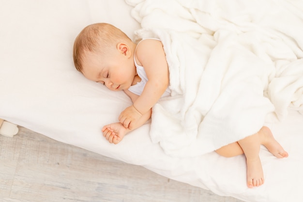 白いベッドで眠っている生後6ヶ月の小さな女の赤ちゃん 健康な赤ちゃんの睡眠 プレミアム写真