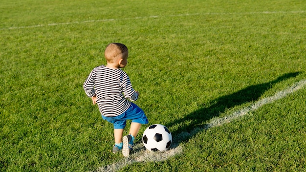 Premium Photo Small Boy Enjoying Himself Running Across A Green Sports Field Kicking His A Soccer Ball In Evening Light