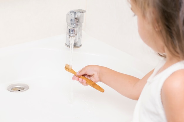A small child brushes his teeth with a bamboo toothbrush. Premium Photo