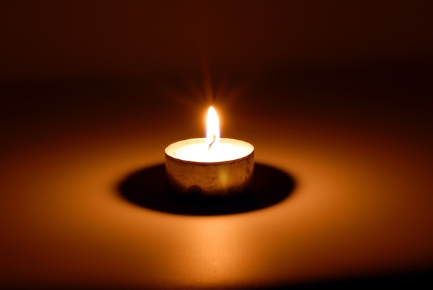 Premium Photo | Small flame of a burning candle in darkness