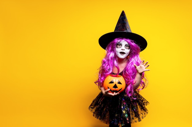 Premium Photo Small Girl In Halloween Witch Dress And Hat Scaring And Making Faces Isolated On Yellow Background Trick Or Treat