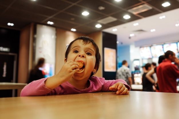 Premium Photo | Small girl sit alone at tabel and eat meal in cafe or ...